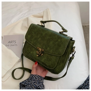 Detail of dark green PU leather handbag with vintage bronze clasp on a stylish background