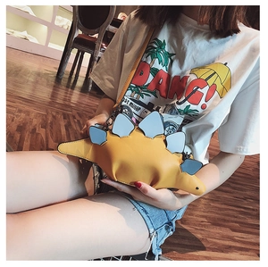 Detailed view of creative yellow dinosaur crossbody bag with blue scales and thin strap