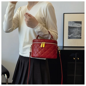 Red quilted bucket bag with gold zippers shown on a shoulder for a stylish look