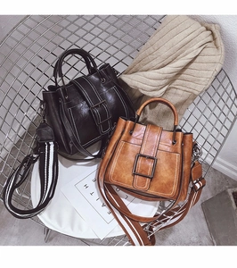 Close-up of vintage matte leather tote bags in black and brown with contrast stitching