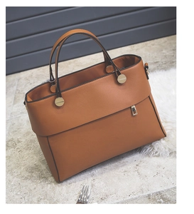 Close-up of brown faux leather tote bag showing side zipper pocket and metal handle hardware