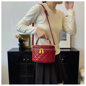 Red quilted leather crossbody bucket bag worn by model in a cozy lifestyle setting