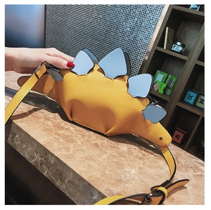 Macro shot of yellow dinosaur crossbody bag showing premium PU leather texture and blue plates
