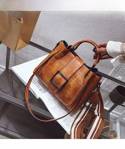 Detail of vintage brown faux leather handbag with wide striped strap and large square buckle