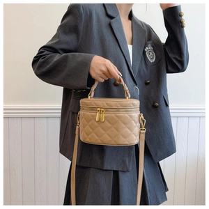 Close-up of light brown quilted bucket bag with gold hardware and adjustable strap