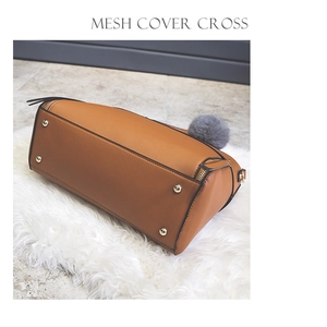 Detailed bottom view of brown tote bag showing golden protective studs and grey fur charm