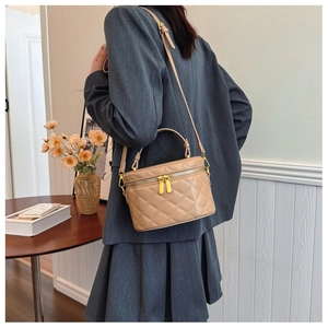 Detail of a beige quilted box bucket bag shown in an elegant commuter setting