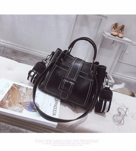 Detail of vintage matte black satchel with white contrast stitching and striped strap