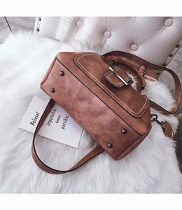 Macro shot of brown matte leather handbag showing base studs and removable strap