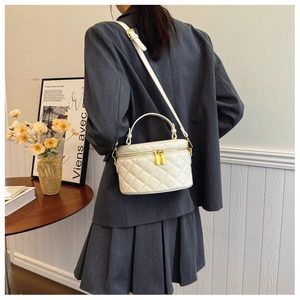 Detail of white quilted leather bucket bag with gold zippers worn on shoulder by model
