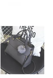 Detail of dark grey tote bag with leather texture, dual handles and grey fur ball charm