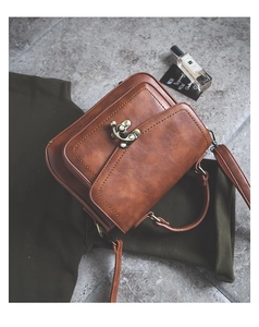 Close-up of vintage brown PU leather handbag with bronze metal lock and top handle