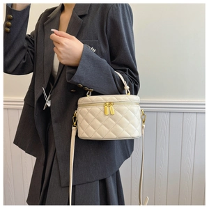 Chic quilted white bucket bag worn by model with structured metal hardware details
