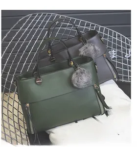 Detail of retro tote bags with side zippers, textured leather and fluffy ball charm