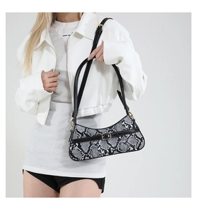Detail of snake pattern leather shoulder bag with a gold metal buckle on black strap