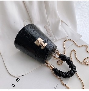Detailed close-up of crocodile texture black bucket bag with gold clasp and chain strap