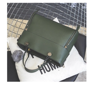 Detail of dark green PU leather tote bag with gold ring hardware and grey pompom charm