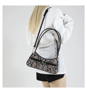 Detailed macro view of gray snakeskin pattern texture and gold buckle on a square bag