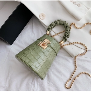 Detail of green crocodile texture bucket bag with ruched handle and gold chain strap