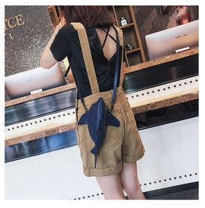 Detail view of a quirky shark-shaped crossbody bag in navy blue leather worn on back
