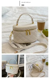 Detailed close-up of cream quilted bucket bag with gold zippers and detachable strap