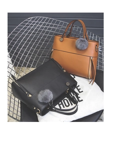 Detail view of tote bags with decorative zippers and fluffy grey fur ball accessories