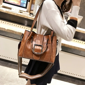 Detail view of brown vintage satchel bag featuring metallic rivets and wide striped strap
