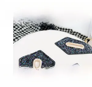 Detailed macro view of sparkling black sequins and gold metal buckle on white leather bag
