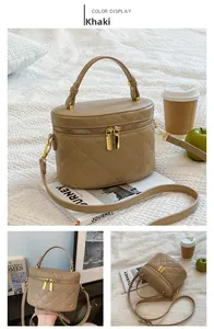 Detail of khaki quilted cylinder handbag with metallic zipper and adjustable strap