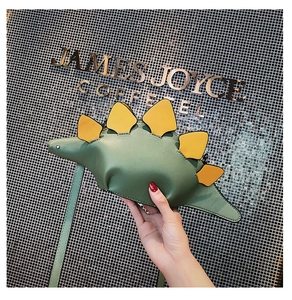 Detail of green stegosaurus dinosaur shaped mini bag made of textured PU leather