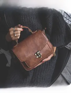 Detail of vintage brown PU leather handbag with antique bronze metal buckle closure