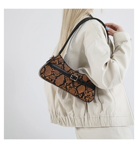 Detail of snake skin texture and metal buckle on brown faux leather baguette bag