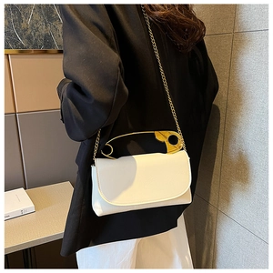 Detail of white envelope bag with unique oversized gold safety pin handle and chain strap