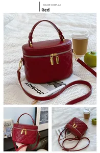 Detail of red quilted cylindrical handbag with gold zippers and polished top handle