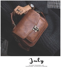 Close-up of vintage brown PU leather handbag featuring a textured finish and retro metal lock
