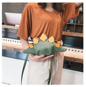 Detail shot of a green dinosaur crossbody bag featuring yellow spikes and a slim strap