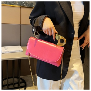 Detail of pink PU leather handbag featuring a unique gold safety pin handle and chain strap