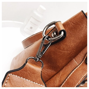 Detail of vintage brown leather bag with gunmetal hardware and white contrast stitching