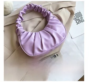 Detail of purple pleated cloud bag showing leather texture on a beige trench coat