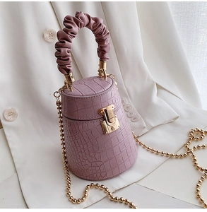 Close-up of purple crocodile pattern bucket bag with gold chain and cloud handle