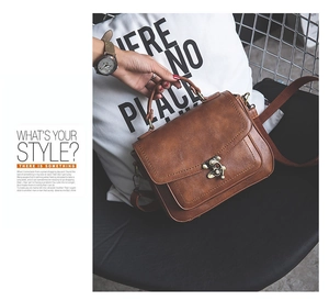 Detail of vintage brown PU leather handbag featuring a retro metal clasp and round handle