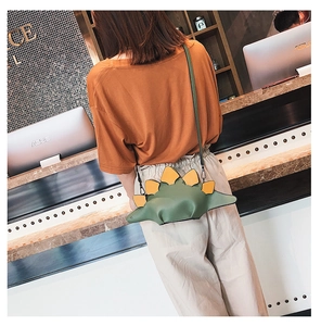 Detailed back view of a mini green dinosaur-shaped crossbody bag with yellow dorsal fins