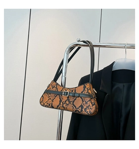 Detailed close-up of brown snakeskin pattern and gold buckle on stylish shoulder bag