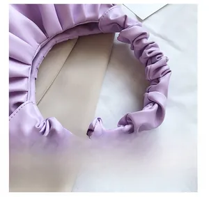 Close-up of light purple dumpling bag featuring ruched strap detail and soft leather texture