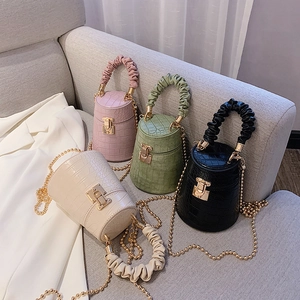 Detail view of four mini crocodile-pattern bucket bags in white green pink and black colors