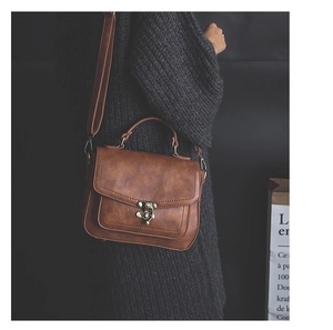 Detail of vintage brown leather bag featuring a retro bronze clasp and fine stitching