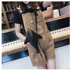 Close-up of a creative black shark-shaped crossbody bag worn by a model in a cafe