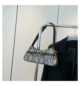 Detailed view of snake skin pattern baguette bag with a gold buckle on display