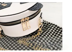 Detail of golden double zipper and metal chain strap on white round sequin panda bag