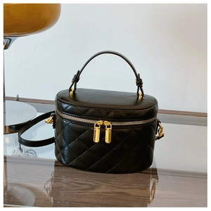 Detail of black quilted leather bucket bag featuring gold hardware and double zippers